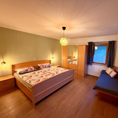 Geräumiges Schlafzimmer mit Doppelbett, Schrank und gemütlicher Sitzecke.