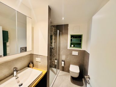 Modernes Badezimmer mit Dusche, Waschbecken und Toilette in neutralen Farbtönen.