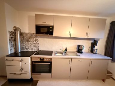 Moderne Küche mit Herd, Backofen, Mikrowelle und Kaffeemaschine. Helle Farbgestaltung.